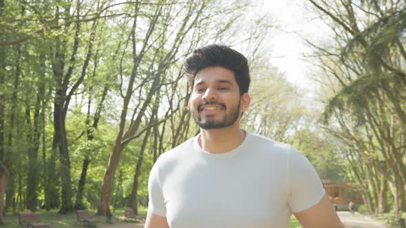 Strong Muslim Man in Activewear Running Alone at Green Summer Park alt
