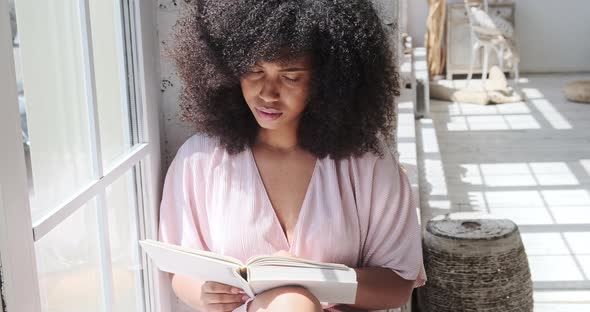 A Young Mixedrace Lady is Attentively Reading an Intriguing Book a Fiction a Novel While Pondering alt