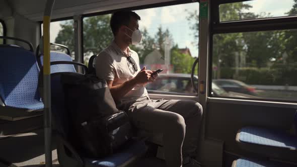 A Passenger in an Ffp2 Mask is on a Bus in Munich at the Window and Browsing the Internet on His alt