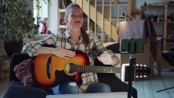 Woman Recording Her Guitar Lesson on Her Phone