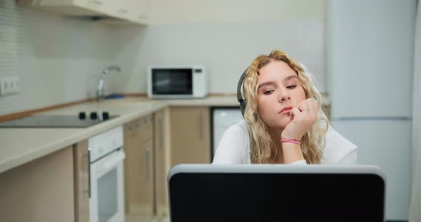 Sleepy Young Woman with Curly Hair Listens To Online Lecture alt
