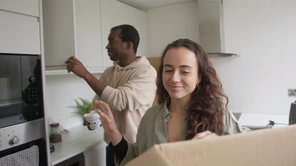Excited Young Couple In New Home Unpacking Removal Boxes In Kitchen Together