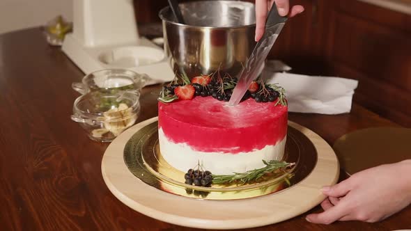 Cook Is Cutting Red Berries Cake , Standing on a Workplace in Kitchen alt