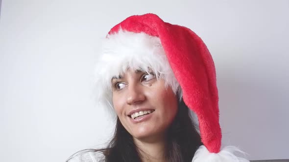Woman in santa claus christmas hat smiling and looking at the camera on a white background close-up