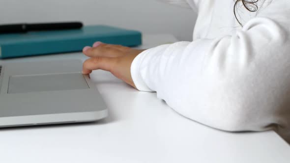 A child girl on distance learning sits in front of a laptop and does homework. alt