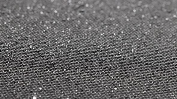 Spinning Background of Black Hydrophobic Fabric While Covering with Water Drops