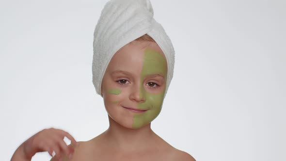 Beautiful Smiling Child Girl Kid in Towel on Head Applying Cleansing Moisturizing Green Mask on Face alt