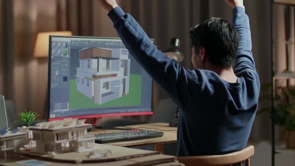 Asian Male Engineer Celebrating While Designing House On A Desktop At Home alt