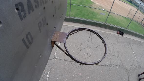 A young man basketball player dunking while playing one on one on an old outdoor basketball hoop alt