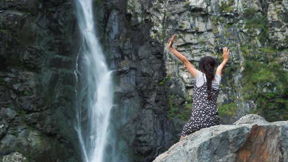 Young Woman Relaxing In Front Of Waterfall