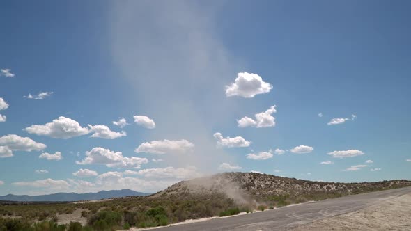 Dirt devil swirling across a road picking up dirt in the Utah desert alt