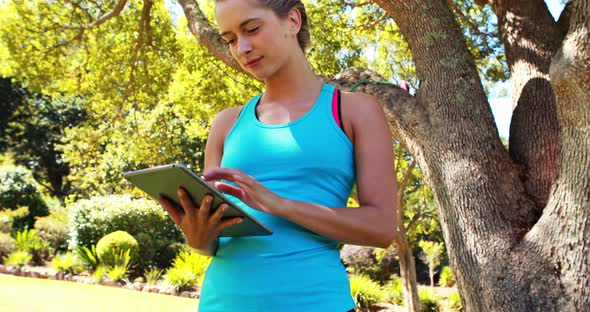 Woman using digital tablet in park alt