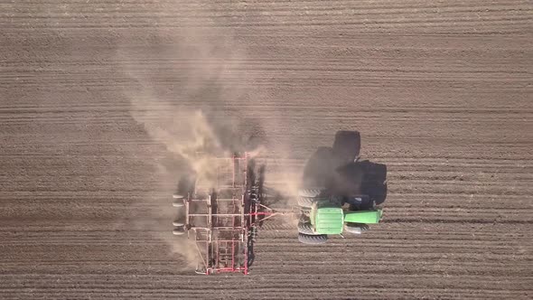 Top Down Aerial View of Green Tractor Cultivating Ground and Seeding a Dry Field alt