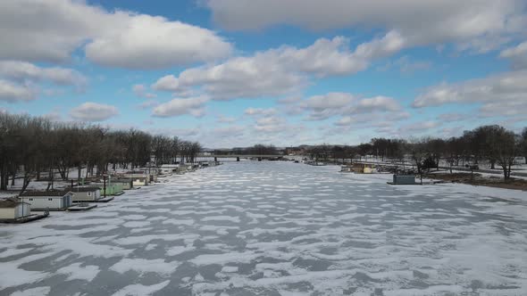 Aerial view down ice covered river in Wisconsin. Beautiful panoramic view with house boats and trees