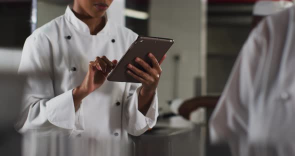 African american female chef using tablet in restaurant kitchen alt