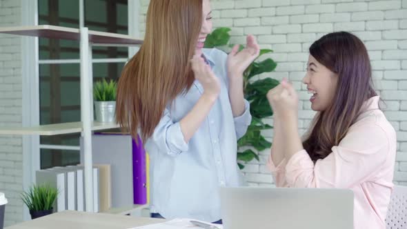 Asian business women feeling happy arms raised celebrating after hear success in office. alt