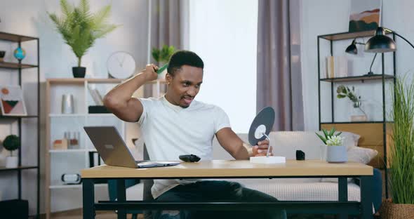 Black-Skinned Man Sitting in front of Small Mirror at Home and Combing His Hair with Special Comb alt