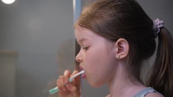 Little Girl Brushing Her Teeth in the Bathroom