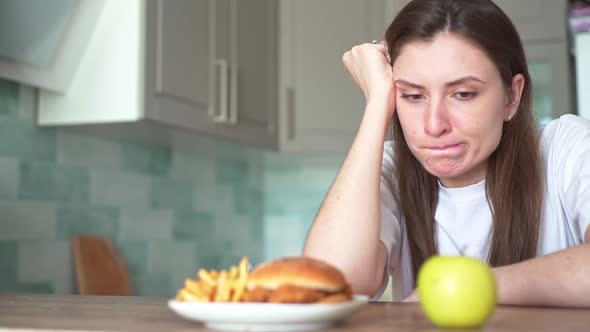 A Young Woman Suffers Because of the Choice of Food Between Harmful and Healthy. The Temptation To