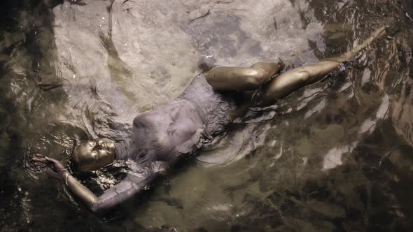 Sensual Golden Woman is Covered Golden Dye is Floating in Shiny Water Top View alt