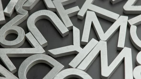 Full Frame Closeup Looped Rotating Background of Silver Metal Letters on Flat Black Surface alt