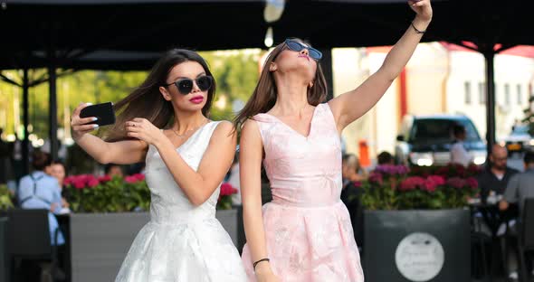 Two Fashionable Woman with Red Lips Making Self Portrait at Smart Phones