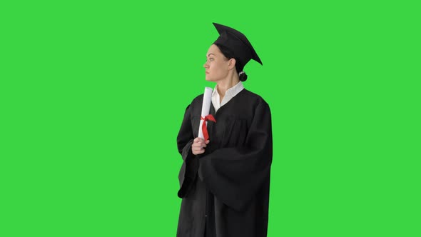 Female Student in Graduation Robe Holding Diploma and Waiving It Around on a Green Screen, Chroma alt