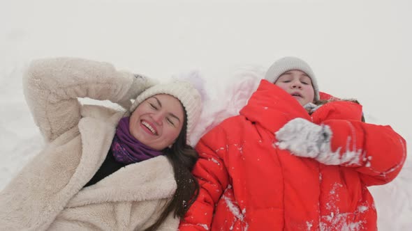 Young Woman and Teenager Girl Lie on the Snow alt