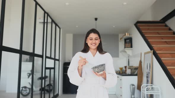 Beautiful Smiling Girl Dressed in White Bathrobe Preparing Breakfast alt