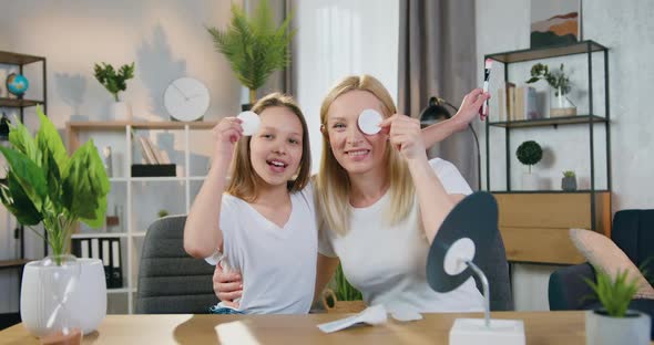 Woman with Teen Girl Putting on their Eyes Cotton Pads and Then Taking Off alt
