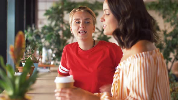 Female Friends Drinking Coffee and Talking at Cafe alt