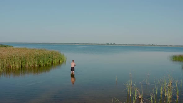 Aerial Drone View. A Man Stands in the Lake and Fishing in Summer Morning alt
