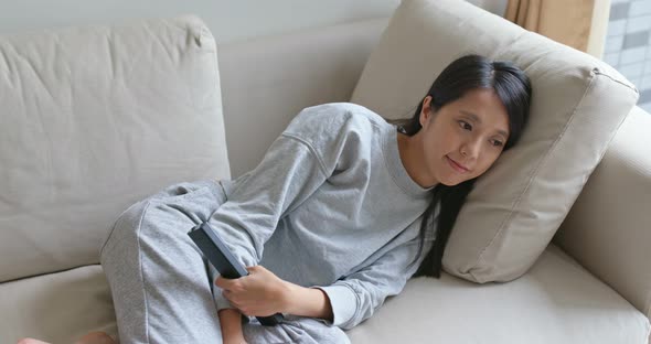 Woman watch tv and lying on sofa at home alt