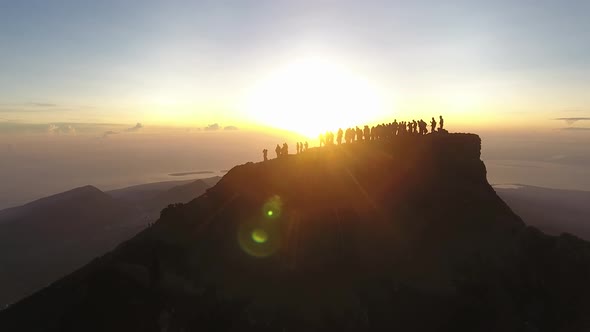 Reveal shot of sunrise over peoples silhouettes on the top of Mt Rinjani alt
