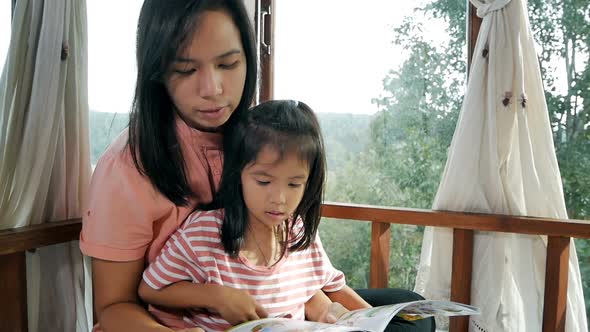 Closeup of mother and daughter reading a book on the bed.