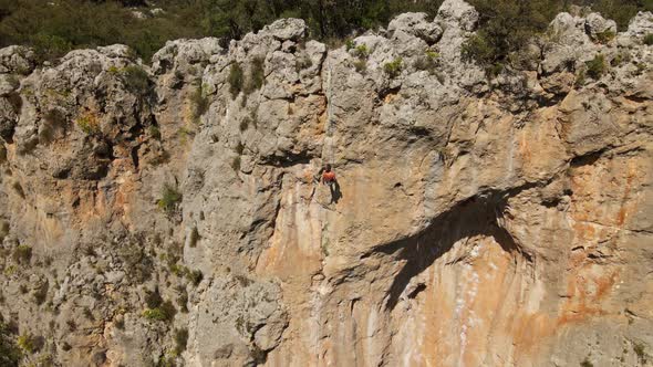 Aerial View From Drone of Strong Athletic Man Rock Climber Descends From High Vertical Cliff on Top alt