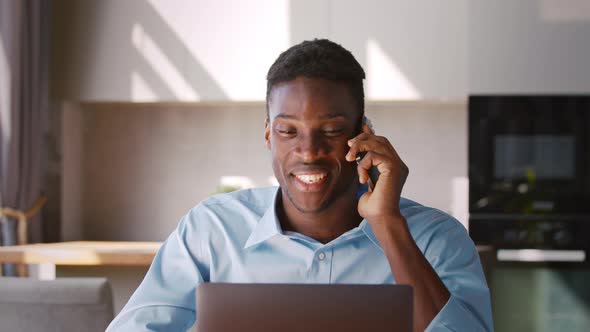 Happy guy talking on phone and looking at laptop screen alt