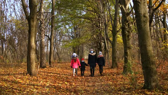 Mother with children in medical masks walks in the Park in autumn