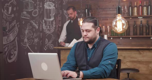Man with Long Hair and Beard Works Remotely and Is Getting a Fresh Coffee alt