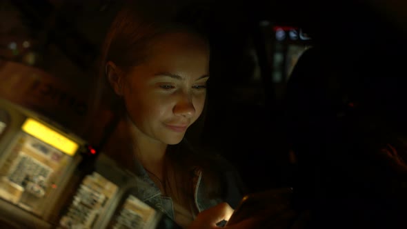 Young Woman Using Mobile Phone While Sitting in a Car at Night