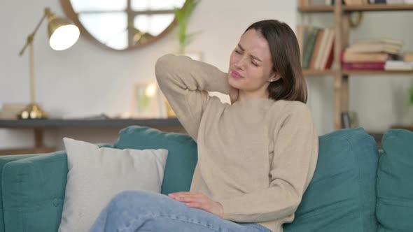Tired Young Woman with Neck Pain Sitting on Sofa alt