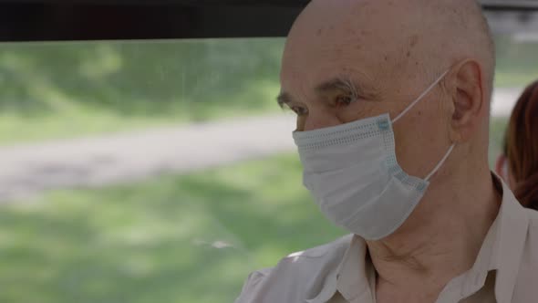 Senior Man in Medical Mask is on a Bus alt