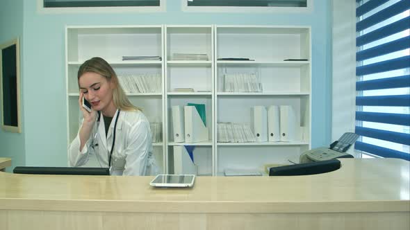 Female Nurse at Hospital Reception Answering Phone Calls and Scheduling Patient Appointments alt