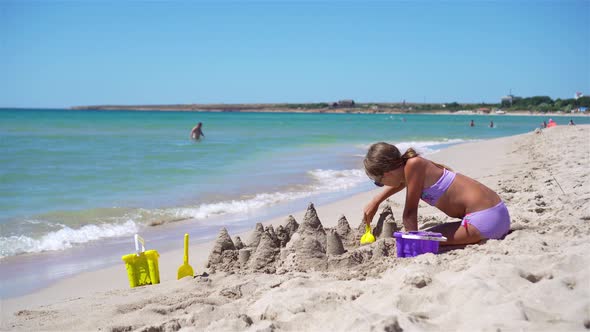 Little Girl at Tropical White Beach Making Sand Castle
