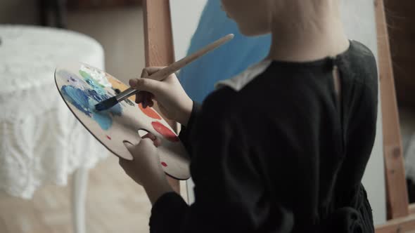 Girl painting on a canvas with paintbrush