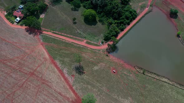 Aerial shot over a farming area of Brazil with roads, cultives and a pond. alt