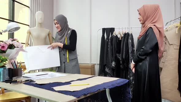 Asian muslim tailor folding dress into the bag and giving to customer