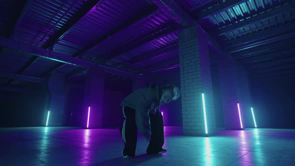 A Steel Woman Dances Hiphop Freestyle in a Modern Style in a Hall with Neon Light in Purple Blue alt