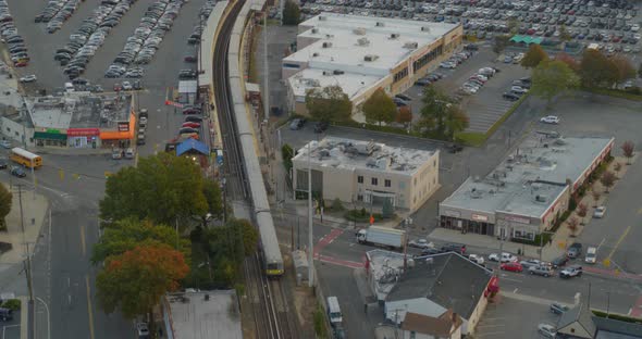 Backwards Aerial Pan Following Shot of a Train Passing Through a Small Town alt