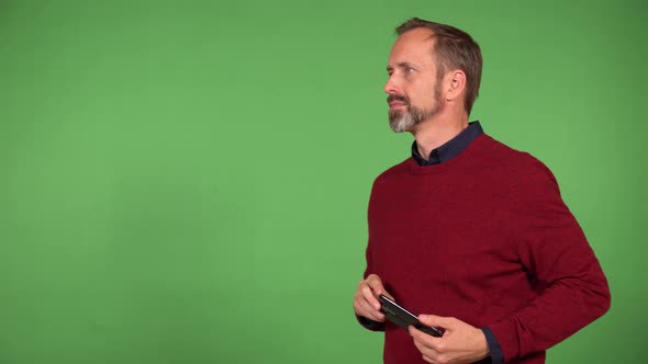 A Middleaged Handsome Caucasian Man Takes Pictures with a Smartphone  Green Screen Background